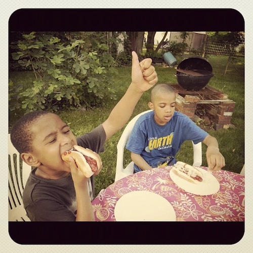 two-boys-eating-hotdogs-summer Two african american boys eating hotdogs outside during the summer